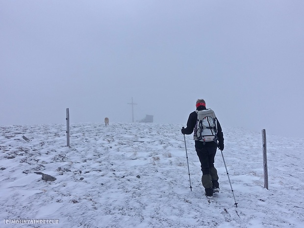 Unvermittelt taucht das Gipfelkreuz aus dem Nebel auf