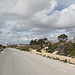 Ta' Dmejrek - Ausblick entlang der oberhalb der Klippen entlang führenden Straße. Hinten ist die Radar-Station zu erkennen. Der höchste Punkt von Malta,Ta' Dmejrek, befindet sich etwa nordöstlich von uns (rechts, hinter den Erdwällen). Am rechten Straßenrand ist auch eine Zufahrt zum Steinbruchgelände zu erahnen. 