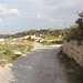 Unterwegs zum Salib tal-Għolja / Laferla Cross - Gerade sind wir am entsprechenden Wegweiser  von der Straße (Siġġiewi - Dingli) abgebogen und gehen nun auf schmalen Sträßchen in Richtung "Laferla". Das Kreuz ist hinten bereits zu erahnen. Am nächsten Abzweig halten wir uns rechts, hinter der Mauer am Wegrand befindet sich übrigens einer der zahlreichen Steinbrüche in diesem Gebiet.