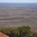 Ausnahmsweise wenig spektakulär, doch informativ: die Straße, die von Yulara (am rechten Bildrand im Hintergrund) zum Uluru führt