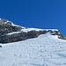 auf den letzten Metern, nun in der Sonne, zum Platz, wo die Skis aufgeschnallt werden;
rechts befinden sich zwei Tourengänger in der seilgesicherten, zu Fuss zu begehenden steilen Aufstiegsstelle neben der mächtig abbrechenden Felswand