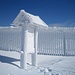 Wetter- und Frost-geformte dicke Schneekruste überzieht Wegtafel und Zaun