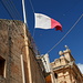 In Qrendi - Blick himmelwärts und zur maltesischen Flagge. Hier auf der Triq il-Parroċċa, kurz vor Rückankunft an der Pfarrkirche (auf dem Rückweg von Il-Maqluba). 