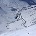 Tiefblick vom Gipfel auf die Oberalp. Die Passstrasse und die Geleise der Matterhorn/Oberalp Bahn schlängeln sich durch die immer noch winterliche Landschaft.