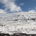 Am Eiðiskarð - Der Ausgangspunkt unserer Tour befindet sich etwas östlich des Passes. Von einer kleinen Fläche am Rand der Straße (Eiði - Gjógv) geht der Blick auf die südlichen Flanken des Slættaratindur. Der Aufstieg erfolgt mehr oder weniger direkt nordwärts bis auf ca. 650 m Höhe. Anschließend wird leicht schräg (deutlich weniger steil) durch die Flanke gequert, der Gipfel dabei unterhalb passiert. An der kleinen Einsattelung zwischen den ganz links sichtbaren, dunklen Felsen und dem Gipfelbereich wird der West-Grat erreicht. Über diesen (oder kurz durch die hier verdeckte Nordflanke) geht's abschließend hinauf auf das Gipfelplateau.