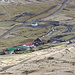 Unterwegs an der Steilküste bei Gjógv - Blick hinunter auf die grasbedeckten Gebäude des Gjáargarður. Bei genauem Hinsehen sind auch etliche Schafe zu entdecken, die sich überall verstreut tummeln.