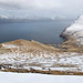 Im Aufstieg zum Fjallið - Ausblick nahe des Gipfelbereichs über die östliche Bergflanke. Durch diesen Hang und anschließend entlang der Steilküste wird später unser Abstieg nach Gjógv erfolgen. Auch das kleine Seelein nahe der Abbruchkante zum Meer ist bei genauem Hinsehen zu erkennen.