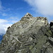 Blick vom Kleinen Ifinger auf das Schlusstück am Gipfelkopf des Großen Ifinger. In Originalgröße kann man das Seil erkennen, dass über ein Wändchen, die Querung und die Felsplatten nach oben führt