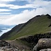 Beim Nebengipfel, Am Fasarinen (903m), hat man dann alle Schwierigkeiten ueberwunden und kann auf einem guten Bergweg (T2) zum letzten Munro, Mullach an Rathain (1023m) wandern. Sieht zwar weit aus, dauert aber kaum mehr als eine halbe Stunde. Links sieht man schon den Meeresarm, Loch Torridon.