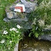 Quelle mit Wegzeichen und Blumenschmuck