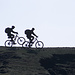 Zwei Mountain-Biker im Gegenlicht an der Tierser-Alpl-Hütte am Morgen des dritten Tages.
