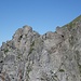 An einem Felszacken auf dem luftigen Grad sieht man (in der linken Bildhälfte) die weiss-blau-weisse Markierung.