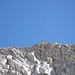 Kräftig herangezoomt: hoch droben zeichnet sich gegen den blauen Himmel das Biv. Orobica (3382 m) ab.