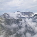 All'arrivo in cresta, le nuovole lasciano intravedere per un attimo il Basodino. In basso, la conca dell'Alpe Formazzöö (Val Calnegia).
