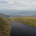 Mangerton Mountain - Ausblick von der Abbruchkante des Gipfelplateaus. Hinten ist das Städtchen Killarney zu sehen, in dessen Umgebung einige Seen liegen. Der größte ist der Lough Leane, in dem auch etliche Inseln zu erkennen sind.