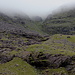 Im Aufstieg zum Carrauntoohil - Nochmaliger Blick auf unsere Aufstiegsroute "Black Mare Ascent". Wo der Felsen (mittig/oben im Bild) den Einschnitt teilt, wählen wir die rechte Rinne. Diese Aufschwünge im Vordergrund umgehen wir rechts (entlang des Flusses, außerhalb des Bildes).