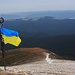 Die Ukrainische Fahne weht über dem Gebirge Чорногора (Čornohora). Gegenüber ist der Гора Кукуль (Hora Kukul’; 1539,4m) zu sehen.