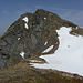 Der Gipfelaufbau wird links vom Schneefeld in steilen Wiesenschrofen erklommen.