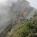 …dann kommt die „richtige“ Schlüsselstelle – der Müller-Kamin. Der Kamin befindet sich rechts der Felswand (Pfeil). Die Wegspuren unterhalb der Felsen nach links führen zur Umgehungsroute  (die Route konnten wir wegen der Nebelschwaden nicht genau sehen)