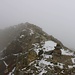 Wegen dem Nebel erkannte ich zuerst nicht einmal den Gipfel und lief dem Grat weiter entlang bis es endgültig wieder steil bergab ging. Auf dem Foto ist der Gipfel von seiner "Rückseite" zu sehen.