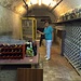 <br />La gentilissima signora Carla hat mir freundlicherweise ihren privaten Weinkeller gezeigt, <br />nachdem sie mich zum zweiten Mal aus dem Wald kommen sah.<br /><br />Diese Cantina an der "Viale alle Cantine" in Mendrisio ist <br />- wie auch viele andere Cantine (Weinkeller) in Mendrisio - <br />direkt in den Berghang unter dem "Casa dei Pagani Tre Buchi" hinein gebaut. <br /><br />Dieser Weinkeller wird durch die Rückwand mittels eines Röhrensystems<br />mit frischer Luft aus dem Wald versorgt.<br /><br />Die Temperatur in diesem  Weinkeller liegt während des ganzen Jahres zwischen 13° und 16°.<br /><br />Die Luftfeuchtigkeit liegt bei 70%.<br /><br />In den andern Häusern an der "Viale alle Cantine" gibt es noch viele andere Weinkeller.<br /><br />Die Cantine an der "Viale alle Cantine" sind terassenförmig in den Berghang <br />unter dem Heidenhaus hinein gebaut.<br /><br />Der private Weinkeller auf dem Bild (oben) befindet sich <br />im 2. Stock eines Terrassenhauses.<br /><br />Oft hat es in einem Haus mehrere Weinkeller, einer über dem anderen.<br /><br />Das und noch vieles mehr über die Weinkeller und Rebhalden von Mendrisio<br />habe ich von der freundlichen und grosszügigen signora Carla erfahren.<br /><br />Grazie mille, signora Carla, per avermi invitato !!!<br />