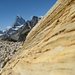 Ein etwas schiefer Blick an schön gefärbtem und geschichtetem Fels vorbei aufs Matterhorn.