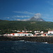 Ilha do Pico - Blick landeinwärts am Hafen von São Roque do Pico/Cais do Pico. Hinten lugt der Pico heraus. Der Schornstein in Bildmitte gehört zur ehemaligen Walverarbeitungsfabrik "Fábrica de Vitaminas, Óleos, Farinhas e Adubos" (bis 1984), heute befindet sich dort das "Museu da Indústria Baleeira".