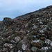 Von den drei grossen Steinmännchen auf dem Kirkjubøreyn stieg ich direkt in Richtung Tórshavn ab. Zwei Felsstufen waren einfach begehbar und meistens konnte ich über Sand oder Gras bergabgleiten. Einzig dieses Schotterfeld unterhalb der Felsen war etwas mühsamer zu begehen.