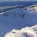 Vom Gipfel zieht ein reifgekrönter Zackengrat in den Schatten. Zwischen lieblichem Fjord und hochalpiner Szenerie sind es jeweils nur wenige hundert Höhenmeter.