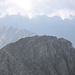 Das Gipfelkreuz der benachbarten, 20m niedrigeren Steinmandlspitze schält sich aus dem Nebel - aber nur für einen kurzen Moment! Im Hintergrund der Lechtaler Hauptkamm mit den vielen Gipfeln der Heiterwand (max. 2639m).