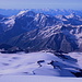 Im Aufstieg zum Elbrus - Ausblick nach Süden: Über die relativ unscheinbaren Pastuchov-Felsen (vorn) und die wesentlich markanteren, geschwungenen Felsen (mit der Diesel-Hütte) geht der Blick nach Garabashi (mit den "Botchki"). Im Hintergrund ist u. a. der für Eingehtouren beliebte (Kleine) "Cheget" (3.456 m bzw. 3.461 m) zu sehen, vor dem alles überragenden Donguzorun.