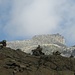 Passo della Rossa con, sullo sfondo, uno dei pochi momenti in cui la Punta di Valdeserta si mostra fuori dalle nuvole. Si nota la forma a trampolino posizionato su verticale pareti rocciose