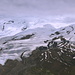 Im Aufstieg zum Cheget - Blick auf die gletscherbedeckte Südflanke des Elbrus (u. a. mit dem Großen und Kleinen Azau-Gletscher). Die Gipfel verstecken sich derweil in den Wolken.