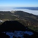 Blick ins Vorland unter einer zähen Nebeldecke, davor der winterlich lange Gipfel-Schatten.