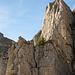 Klettersteig Fruttstägä vom Wanderweg aus. In Originalgrösse kann man das Bänklein mitten in der sonnenbeschienenen Felswand gut erkennen.