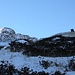 <b>Dai 2000 m circa si vede l’omino di pietre che precede il Rifugio Alp d’Arbeola. Lo raggiungo serpeggiando fra cespugli di rododendro e erbe secche che emergono dalla neve. </b>