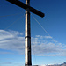 Gipfelkreuz vor den verschneiten Bergen des Nordtessins