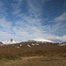 Unterwegs auf Snæfellsnes - Mittlerweile liegt die Tour zum Snæfellsjökull hinter uns und wir besuchen noch einige Sehenswürdigkeiten und Orte der Halbinsel. Während eines Zwischenstopps blicken wir dabei über einige vorgelagerte Berge hinweg zum Snæfellsjökull, wo sich gerade die letzten Wolken verziehen.