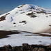 Im Abstieg vom Geldingafjall - Der Ausgangs- und Endpunkt unserer Wanderung am Vatnsskarð ist nun gleich wieder erreicht. Der kleine See am Pass ist zur Zeit noch gefroren und schneebedeckt, wie etwa in Bildmitte zu erkennen ist. Dahinter erhebt sich der Sönghofsfjall (648 m).