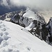 Blick vom Gipfel zum Hintergrat, und etwas rechts von der Bildmitte zwei Bergsteiger, die diesen Weg zum Gipfel gewählt haben