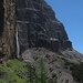 Eindrucksvoll geht es unter Felswänden entlang; ein Wasserfall rauscht in die Tiefe. Rechts daneben der schätzungsweise 100 m hohe Klettersteig Minighel.