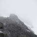 Die 25m Kletterstelle. Oben sieht man einen Bergsteiger. Gegen links hinten (es sind ebenfalls zwei Leute zu sehen) ist die Passage der "Alustangen" zu sehen. Und auf der rechten Seite, eher unten, schon leicht im Nebel ist nochmals eine Person zu sehen. Dort ist gleich der Übergang zum Gletscher, über eine kleine Felsstufe recht gut zu erreichen!<br />(Bild im Abstieg aufgenommen)