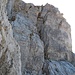 Zwischen ihnen hindurch geht es an einen grasigen Riss links von einem bauchigen Felsen. In den Riss gelangt man von links.