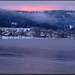 Morgenrot spiegelt sich auf dem halb zugefrorenen See.