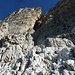 21 Die Bergsteiger umsteigen den kleinen Felskopf vor der gelben, schattigen Verschneidung nach rechts und queren zum Kamin. Dieser ist hier nicht zu erkennen.