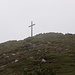 Das namensgebende Kreuz auf dem Croix de Mézenc, Nebelschwaden ziehen über das Gelände.