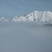 Blick zu aus dem Nebel herausschauenden Bergen.