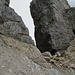 08 Der in den Fels des Torre di Forcella della Grande geschlagene Alpini-Unterstand teilt die Westliche-Zinnen-Scharte in zwei Teile. Hier leitet ein verwaschener oranger Pfeil in...