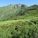 Eccoci ai prati della bella Alpe di Corte Lagoni, ormai abbandonata e preda dei primi arbusti colonizzatori (mirtillo nero e rododendro), ora dovremo risalire i dossi visibili a destra, per portarci alla Bocchetta di Revolte (1.981 m).