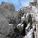 Der kurze Kamin bereitet keine Schwierigkeiten (knapp II), aber danach kraxelt man noch eine Weile weiter aufwärts bis zum Einstieg in die Südwand-Querung
